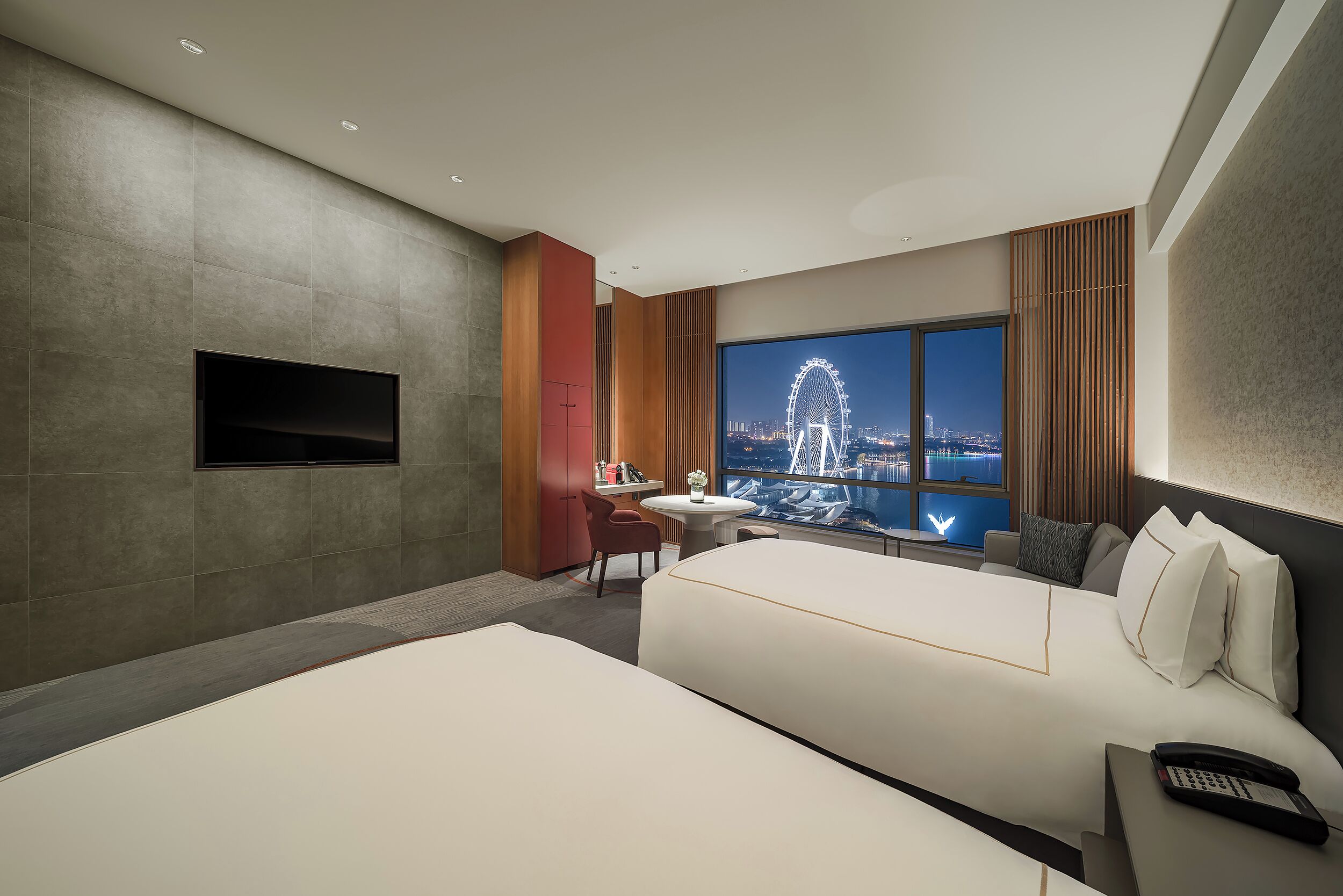 A modern hotel room with a large bed, a desk, and a TV mounted on the wall.