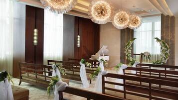 A church interior with wooden pews, a piano, and floral decorations.