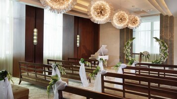 Een kerkinterieur met houten banken, een piano en bloemdecoraties.
