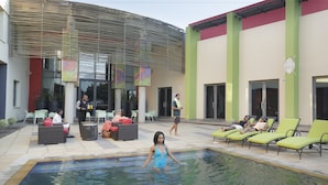 A swimming pool area with lounge chairs and a covered seating area. - Peermont Metcourt Hotel at Umfolozi (Empangeni)