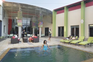 Una piscina al aire libre, sillones reclinables de piscina