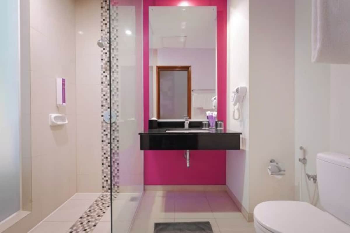 A bathroom with a glass shower enclosure, a black sink, and a white toilet.