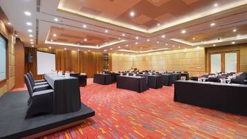 Un salón de conferencias con varias mesas, sillas y un escenario.