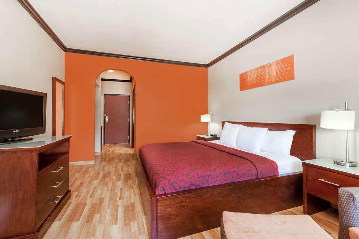 A hotel room with a bed, a TV, a desk, and a chair.