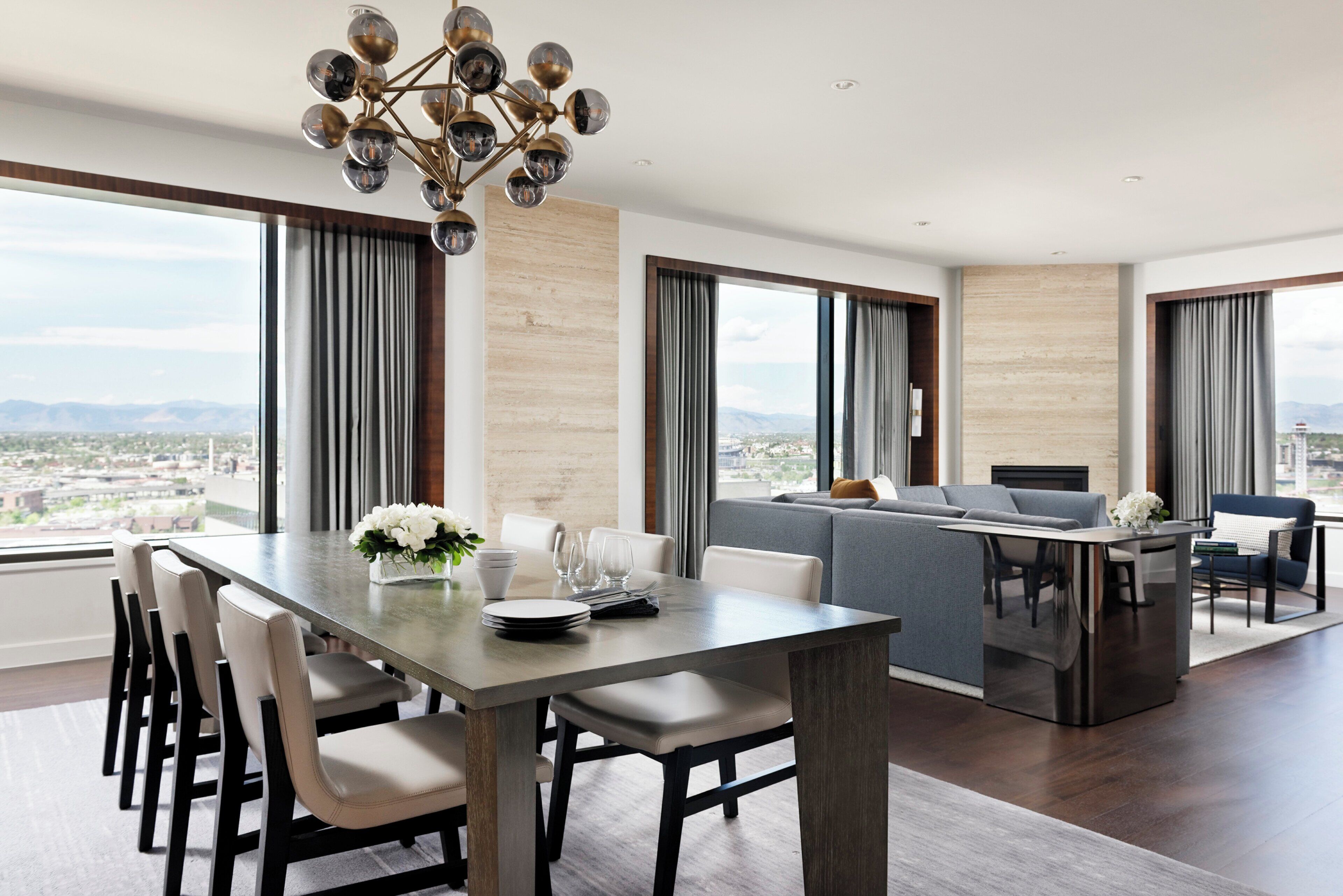 A modern dining area with a large table, chairs, and a chandelier.