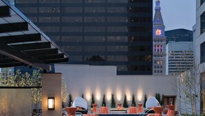 Terraza en la azotea con mobiliario exterior, piscina y vista a una torre de reloj.
