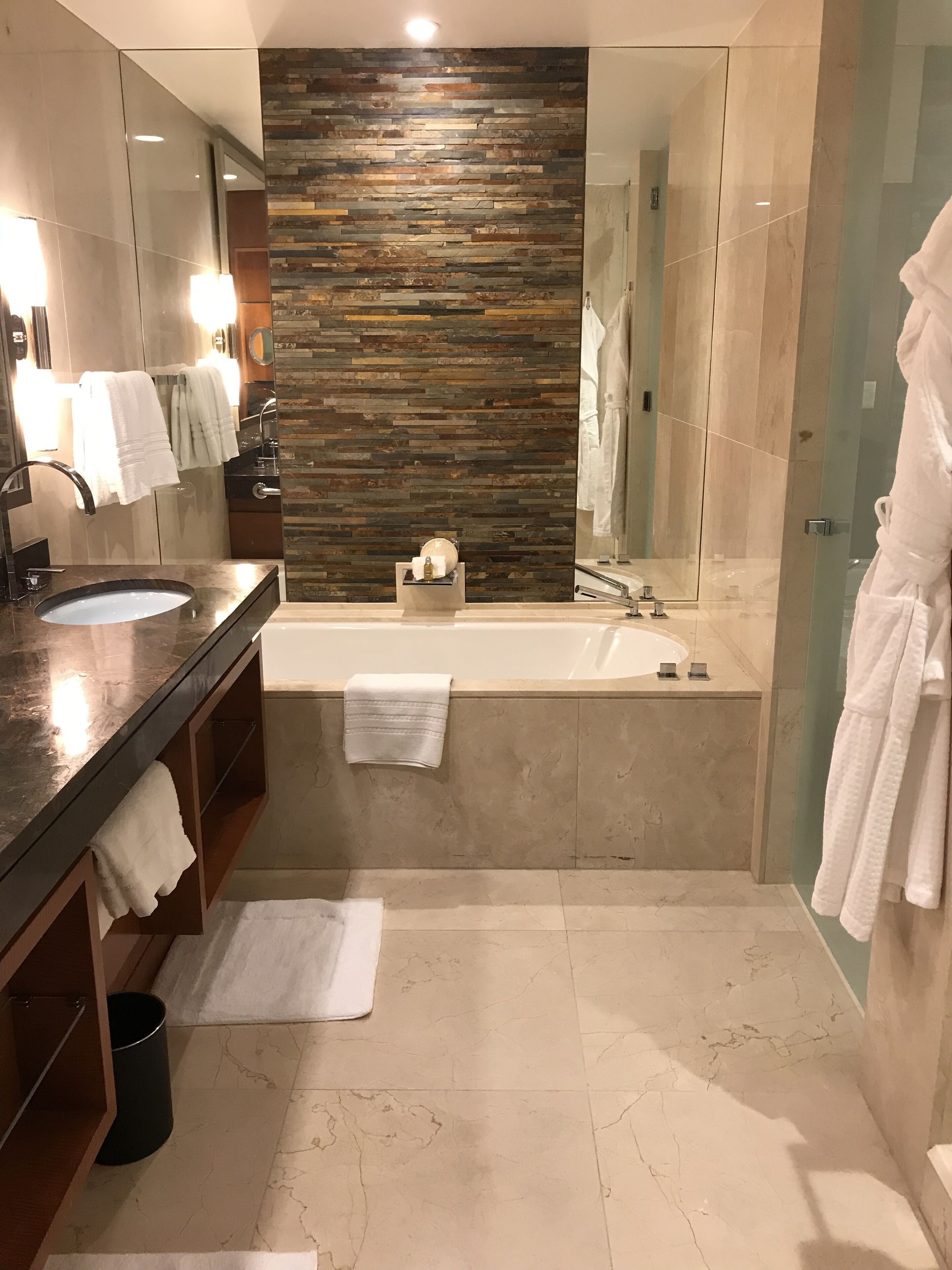A modern bathroom with a large mirror, a bathtub, and a vanity with a sink.