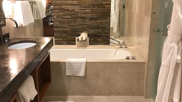 A modern bathroom with a large mirror, a bathtub, and a vanity with a sink.