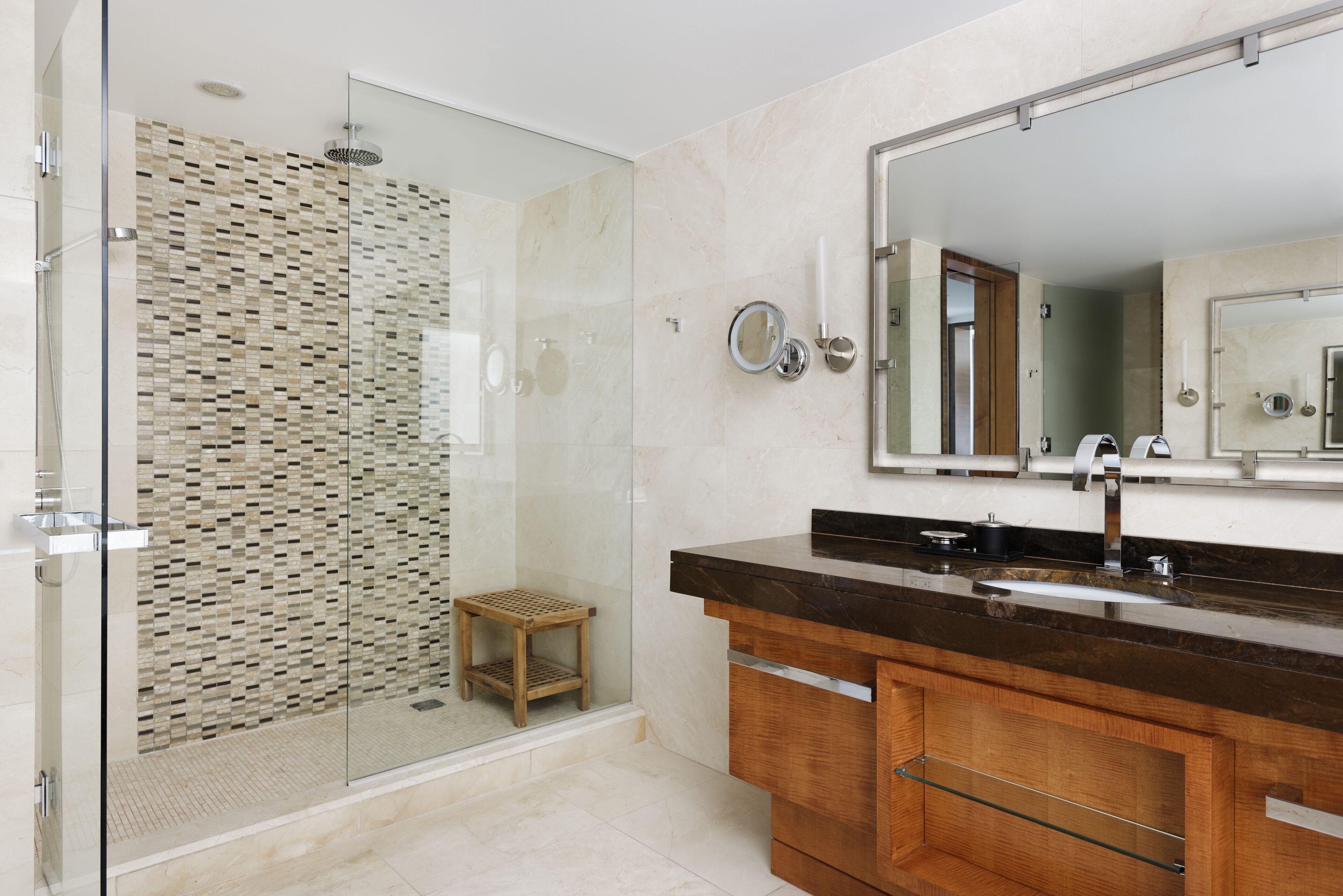 A modern bathroom with a glass-enclosed shower, a wooden vanity, and a large mirror.