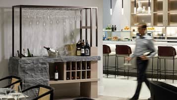 A modern bar area with wine bottles, glasses, and a seating arrangement.