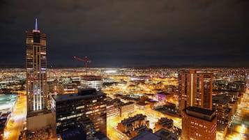 Un paisaje urbano nocturno con edificios iluminados y un rascacielos destacado con una luz azul en la cima.