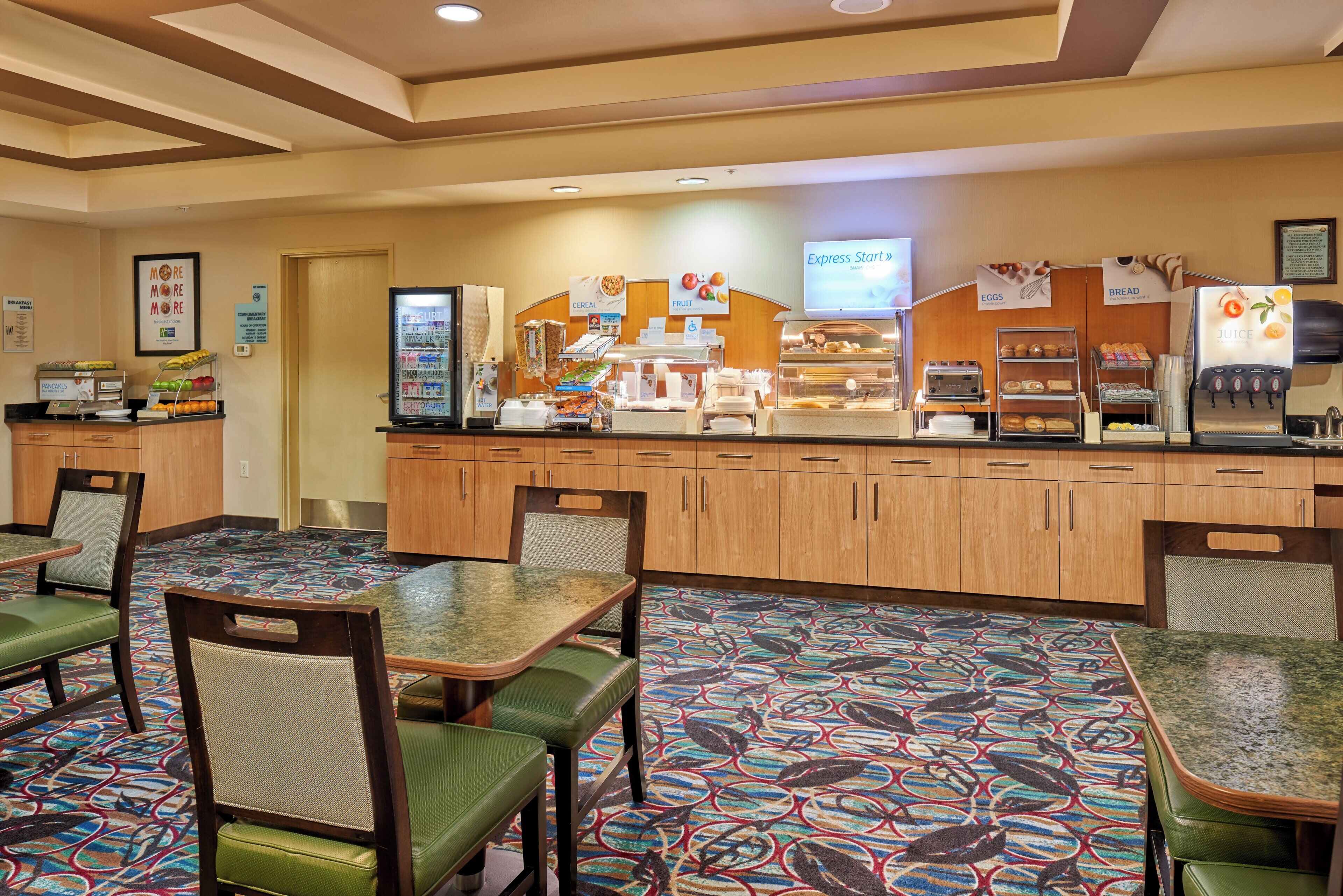 A breakfast area with a buffet, seating, and a juice dispenser.