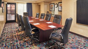 A conference room with a long table, multiple chairs, a patterned carpet, and a door leading outside. - Holiday Inn Express & Suites El Paso Airport Area by IHG (El Paso)