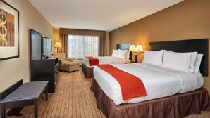 Quarto de hotel com duas camas, uma escrivaninha, televisão e janela com cortinas.