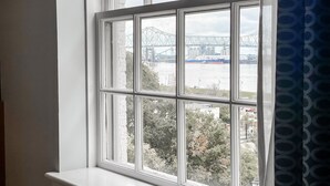 A window with a view of a bridge and industrial structures across a body of water.