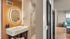 A modern bathroom with a large mirror, a shower, and a sink.