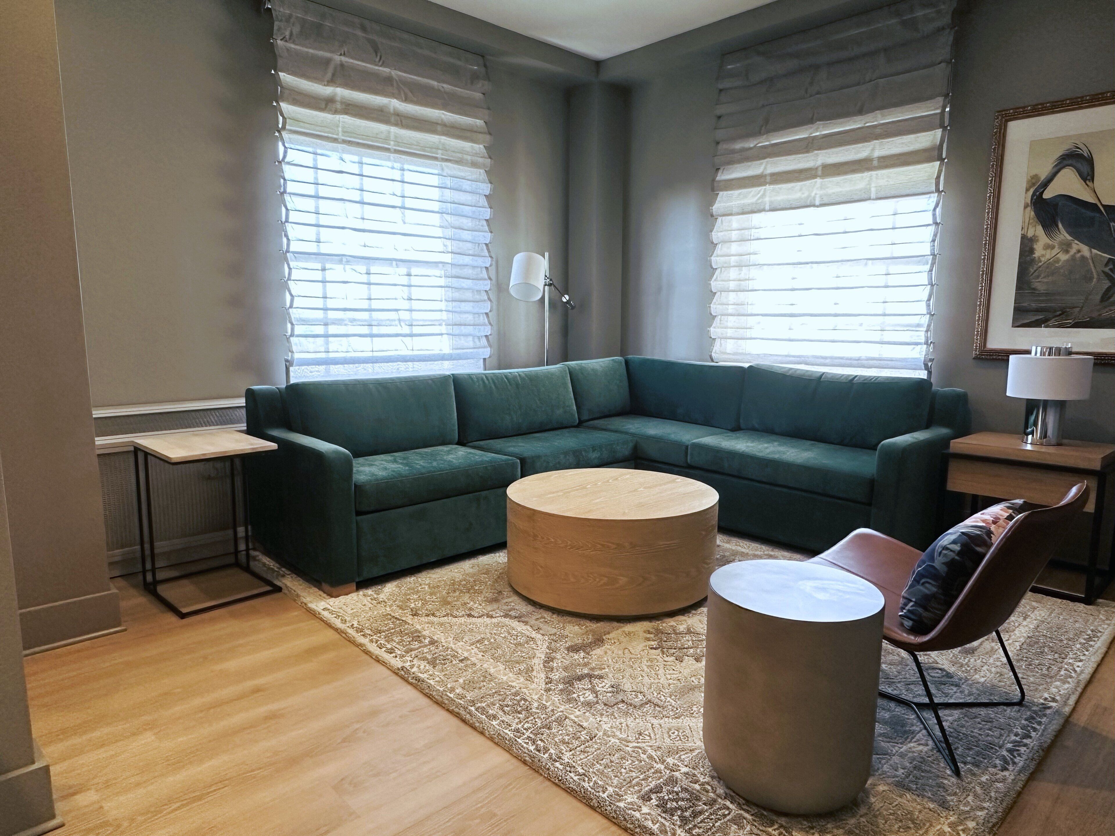 Uma sala de estar moderna com um sofá seccional, uma mesa de centro redonda, uma mesinha lateral e um abajur.