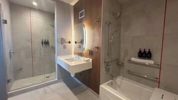 Un baño moderno con ducha de vidrio, lavamanos blanco con espejo y bañera.
