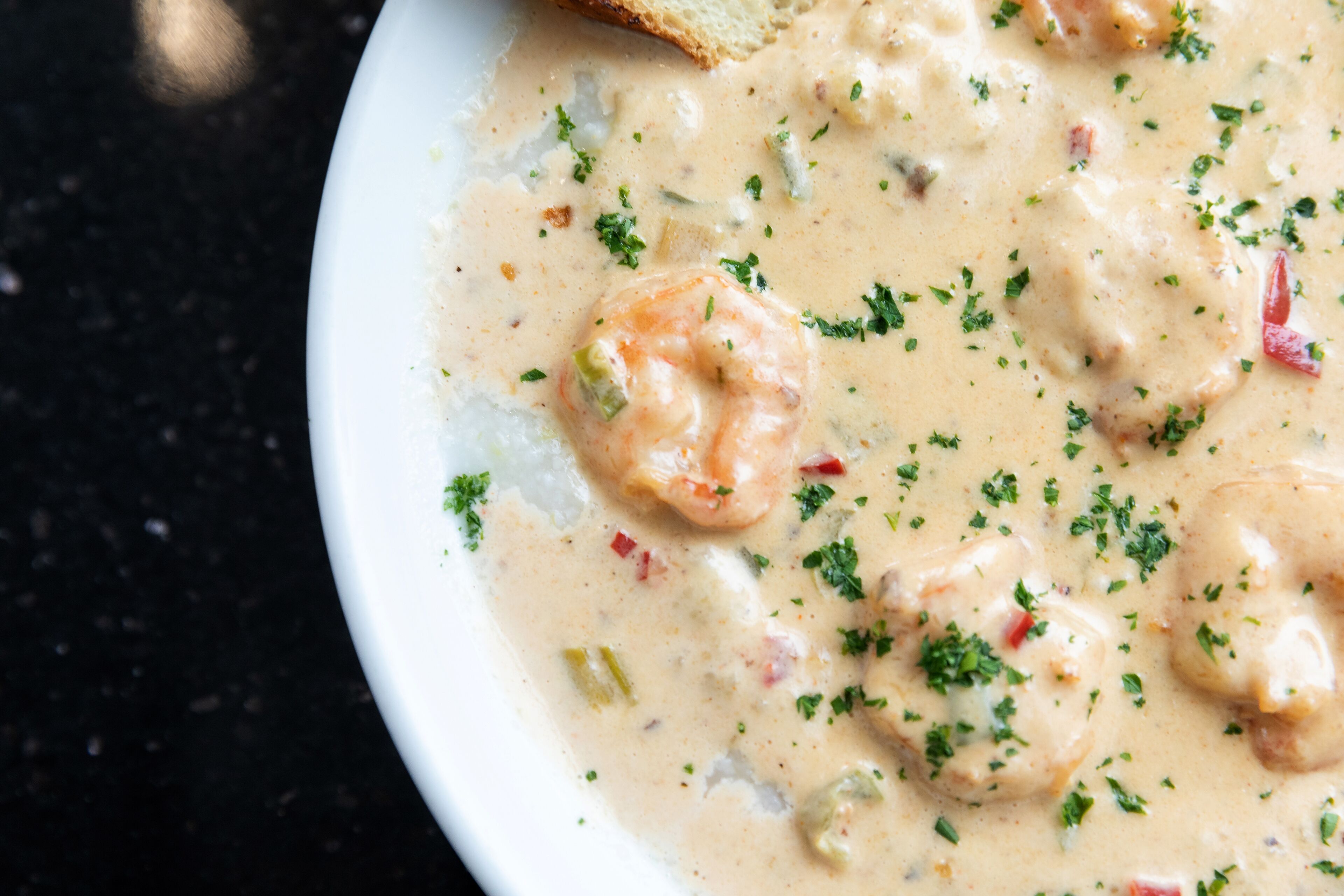 A bowl of creamy seafood soup with shrimp and herbs.