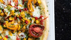 A pizza with various toppings on a white plate.