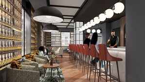 Uma área de bar moderna com um balcão comprido, banquetas vermelhas e uma grande estante cheia de garrafas.