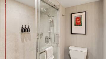A modern bathroom with a glass-enclosed shower, a white toilet, and a framed picture on the wall.