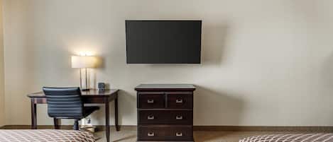 A hotel room with a bed, a desk with a chair, a dresser, and a flat-screen TV mounted on the wall.