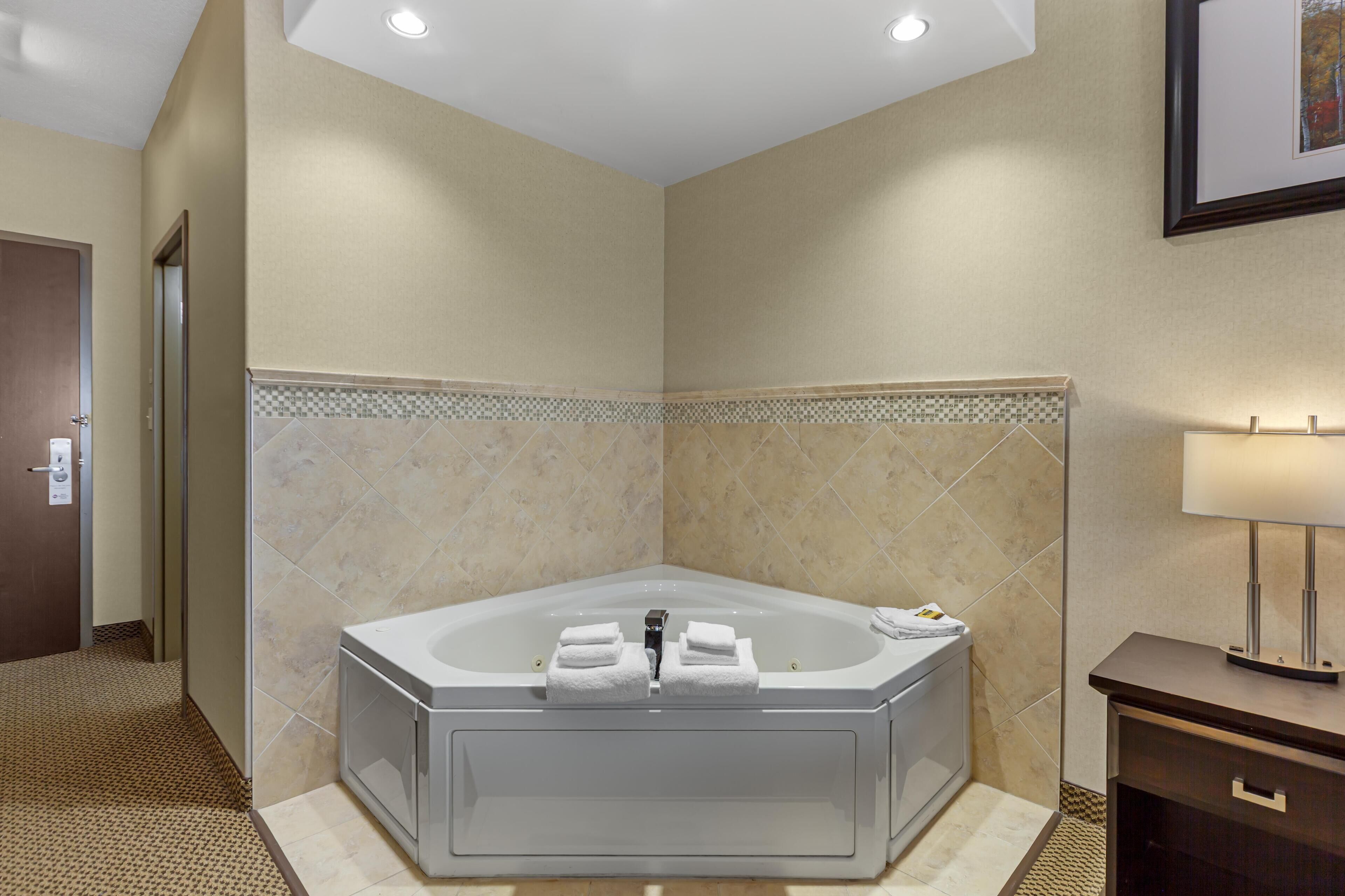 A modern bathroom with a large bathtub, a shower area, and a vanity with a lamp.