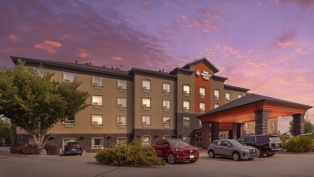 Ein Hotel mit modernem Design, das einen überdachten Eingang und mehrere Parkplätze bietet.