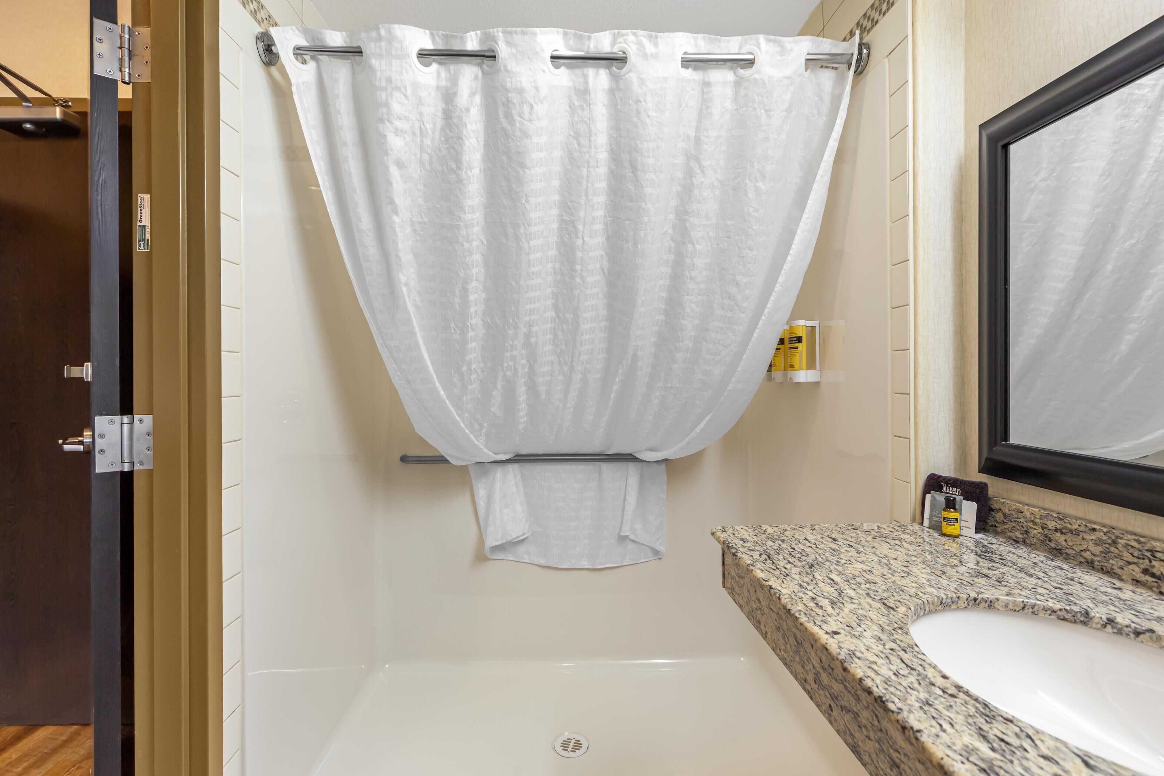 A bathroom with a shower curtain, a sink, and a mirror.
