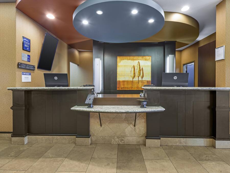 A reception desk with two HP computers, a large painting on the wall, and a sign indicating the check-in desk location.