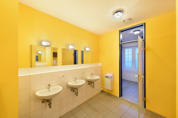 A bathroom with three sinks, a mirror, and a door leading to another room. - Bed'nBudget Expo-Hostel Rooms (Hannover)