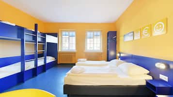 A room with bunk beds, a desk, a chair, and a bed with white linens.