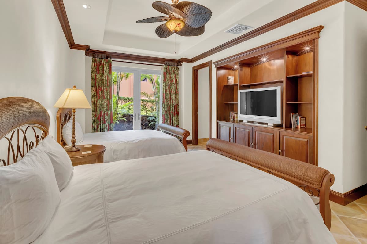 Une chambre d’hôtel avec deux lits, une télévision, un ventilateur de plafond et une vue sur l’extérieur.