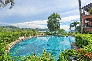 A swimming pool surrounded by lush greenery and a view of distant hills.