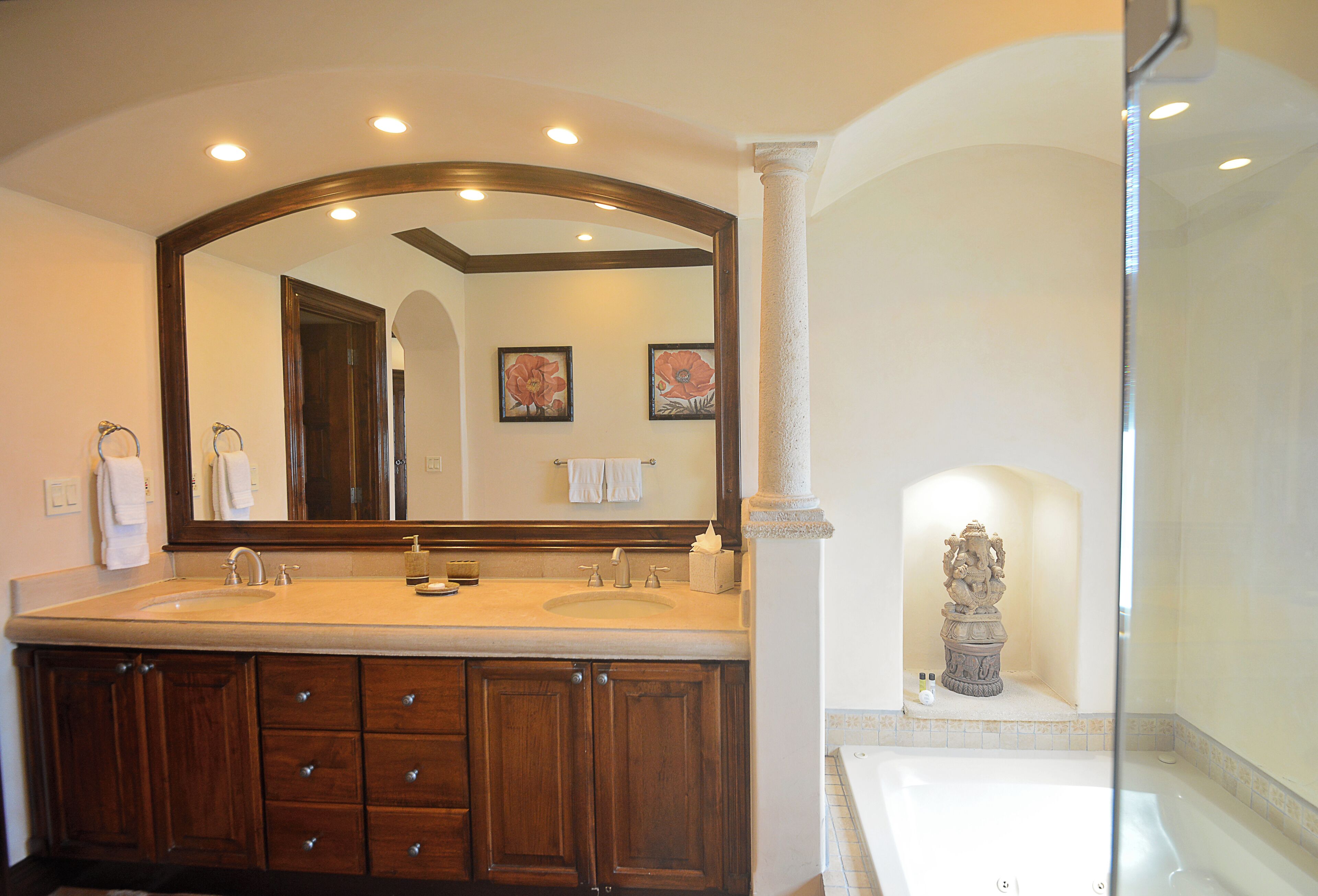A bathroom with a double sink vanity, a large mirror, and a statue in the corner.