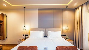 A modern hotel room with a large bed, two bedside tables, a mirror, and a nightstand.