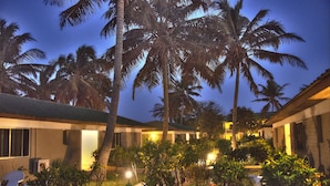 A hotel courtyard with palm trees, a pathway, and a seating area at dusk.