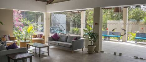 A spacious lobby with a grey sofa, a coffee table, and a potted plant.