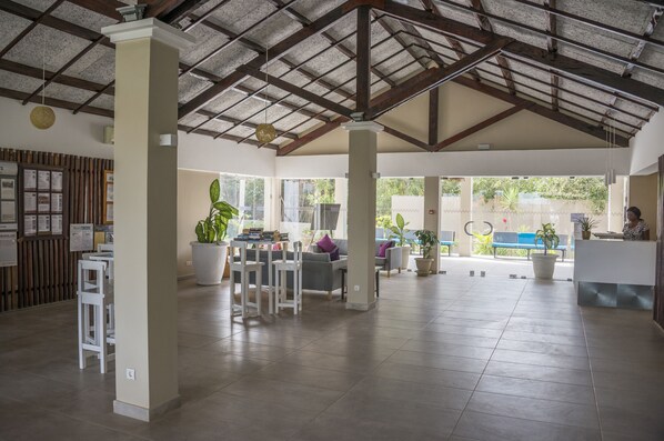 Un vestíbulo amplio con techos altos, ventanas grandes y una mesa de recepción.