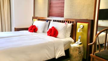 Una habitación de hotel con una cama doble, dos almohadas, una mesita de noche con lámpara y una silla.