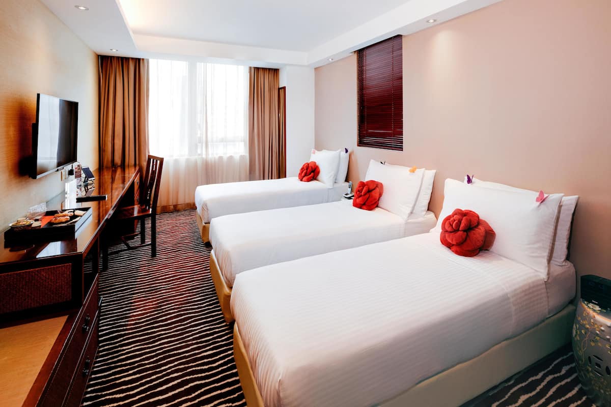 A hotel room with two beds, a desk, and a TV.