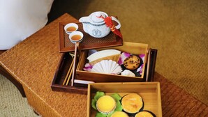A traditional Japanese tea set with a teapot, cups, and a small tray with chopsticks, a fan, and a decorative item on a woven mat. - Butterfly on Wellington, Central (Hong Kong)