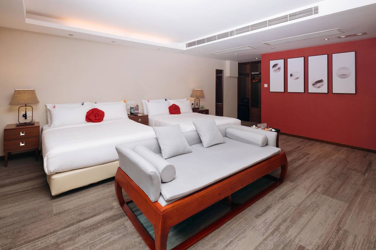 A modern hotel room with a large bed, a sofa, and a desk.