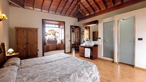 A bedroom with a large bed, wooden ceiling, and a view of the outside. - Hotel Rural Bentor (Los Realejos)