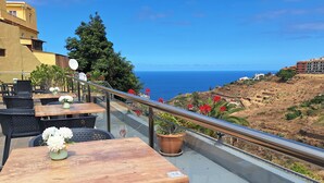 A terrace with outdoor seating, a railing, and a view of the sea. - Hotel Rural Bentor (Los Realejos)