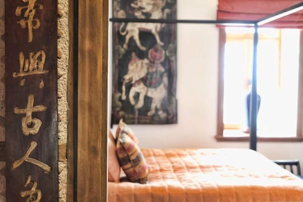 Ein Schlafzimmer mit einem Bett, einem Kissen, einer Wand mit einem Gemälde und einer Holzwand mit Schrift.