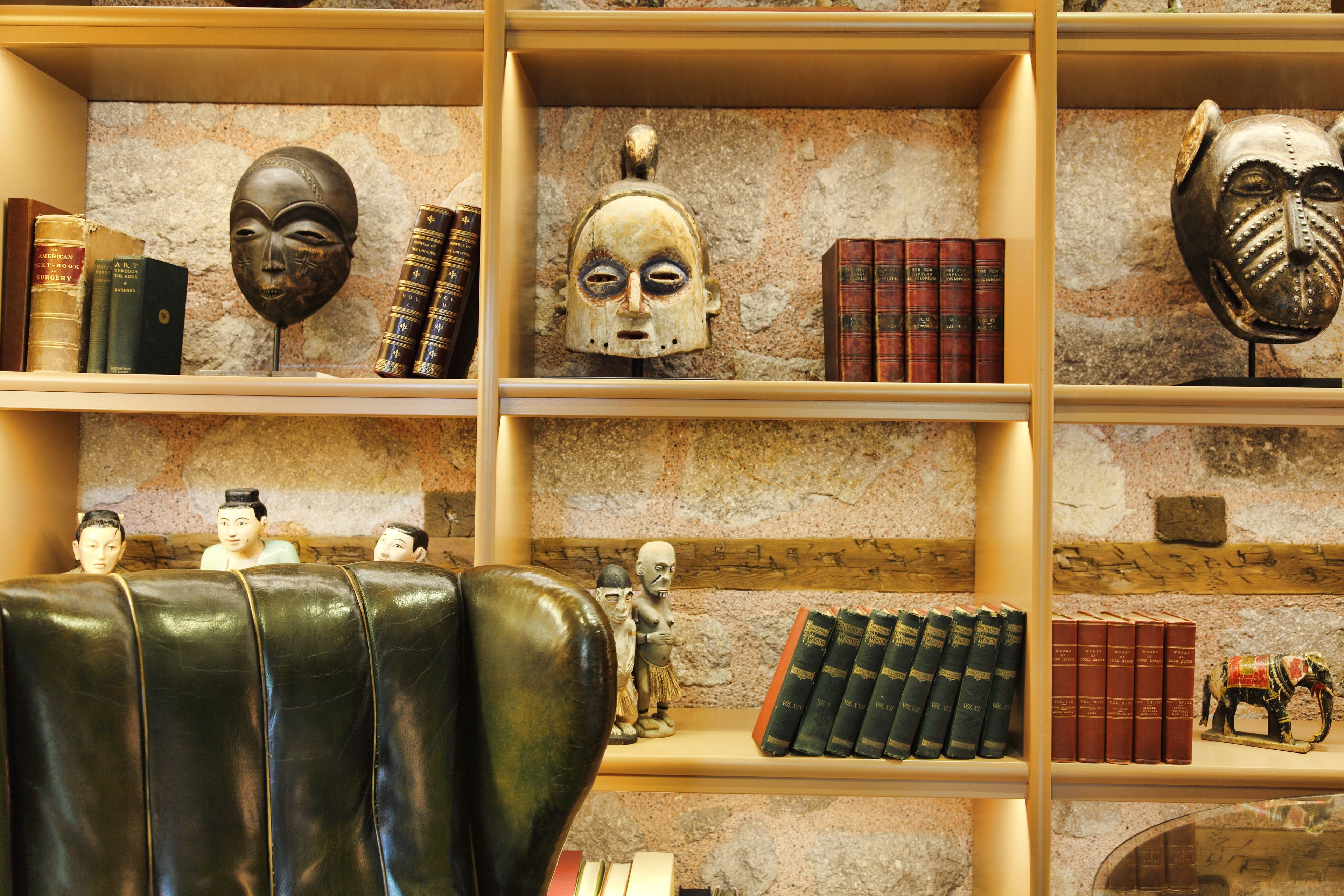 A library with shelves of books and decorative masks.