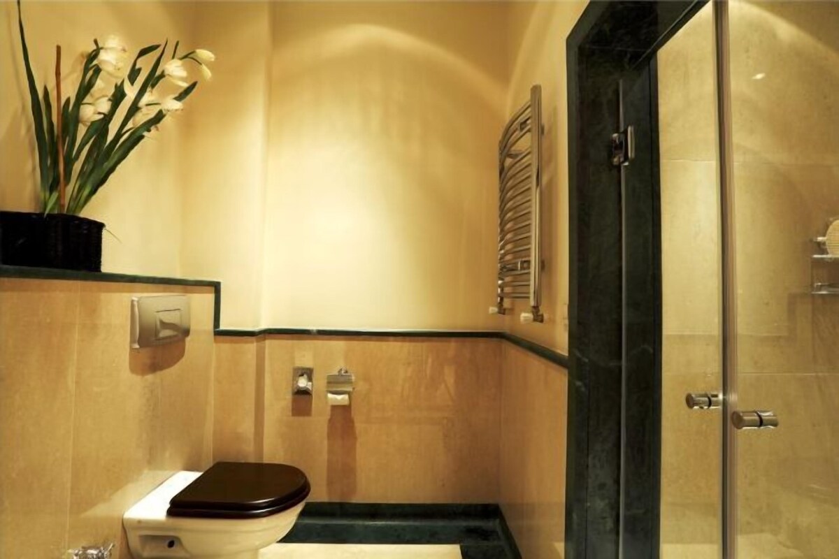 A bathroom with a toilet, a sink, a shower, and a potted plant.