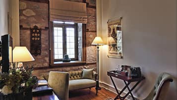A cozy room with a stone wall, a cushioned sofa, a wooden table, and a floor lamp.